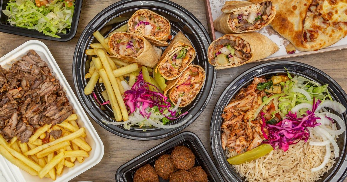 A spread of freshly prepared shawarma wraps, grilled meat, rice, fries and sides